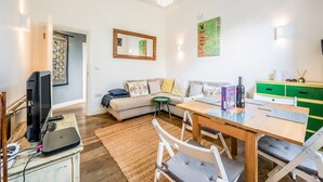 A living room with a sofa, coffee table, and a dining area with chairs. - Cozy, cute flat in Notting Hill - Pass the Keys (London)