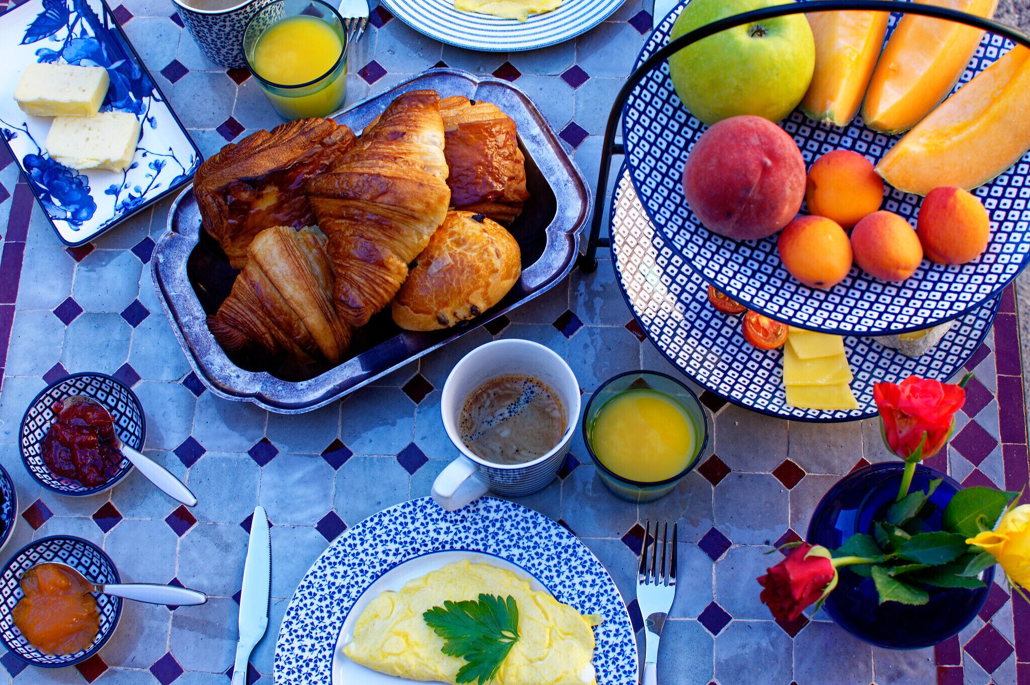 A breakfast setting with croissants, fruits, and a plate of eggs.