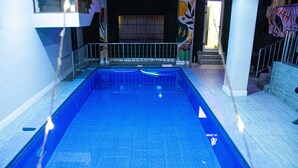 En swimmingpool med flisebelagt gulv og gelænder.