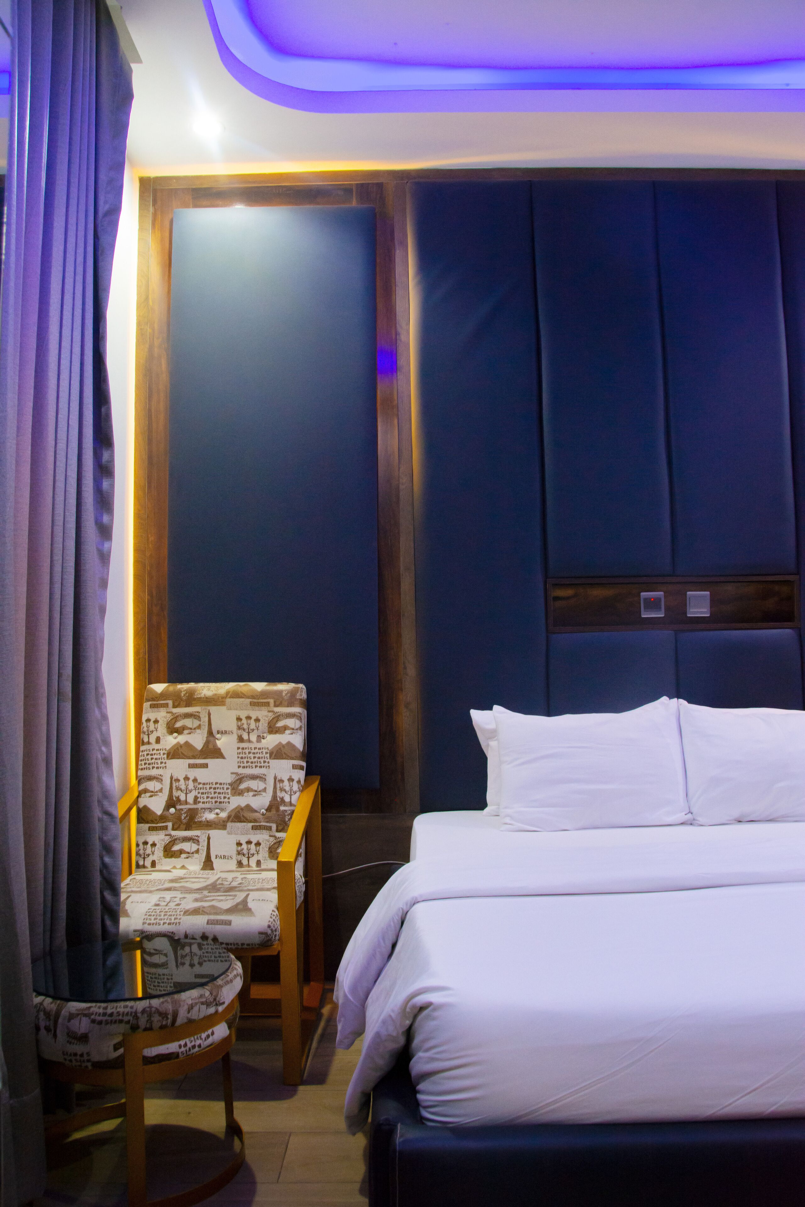 A hotel room with a bed, a chair, and a small table.