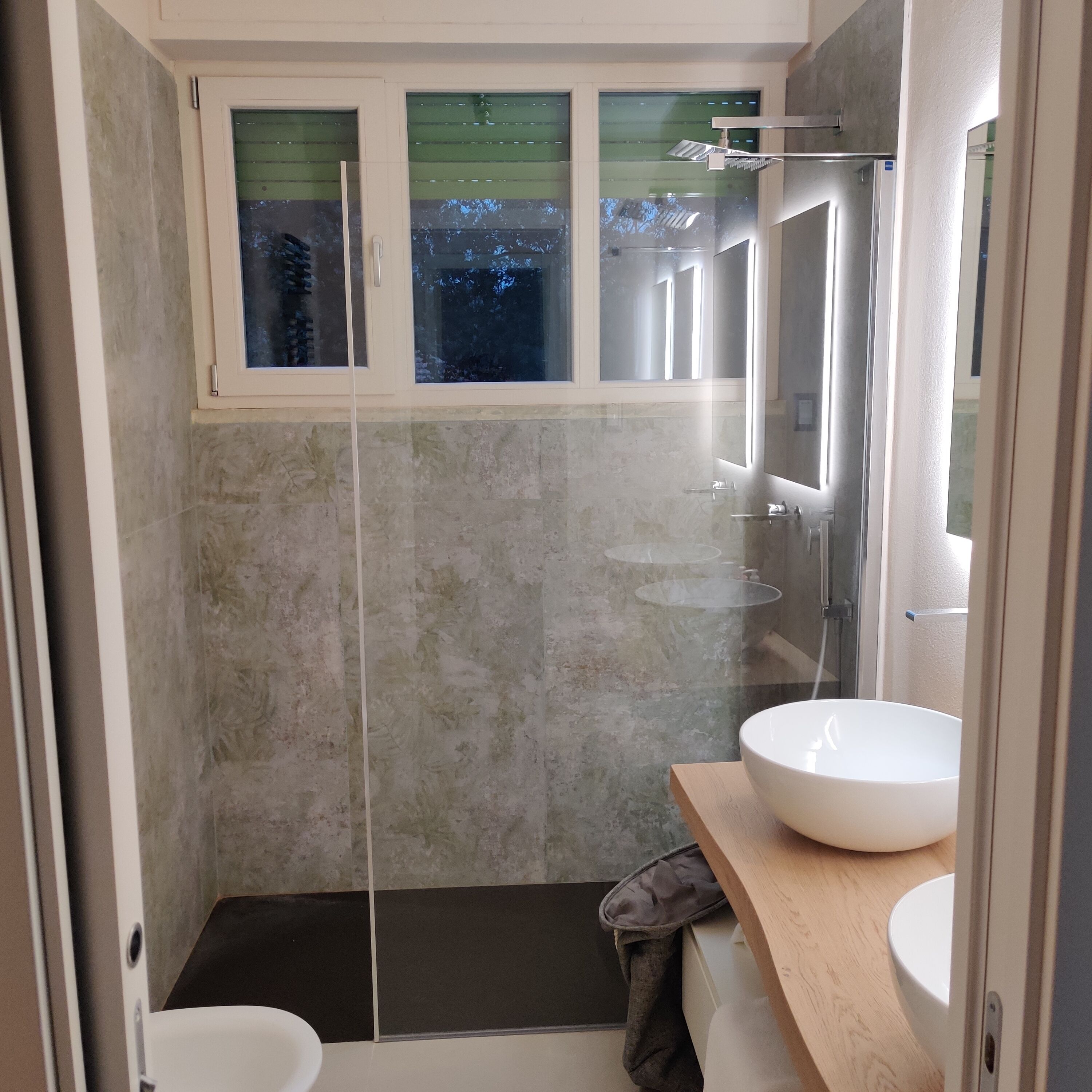 Un baño moderno con cabina de ducha de vidrio, un lavabo blanco y un espejo.