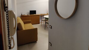 Ein modernes Wohnzimmer mit einer Couch, einem runden Spiegel und einem Fernseher auf einem Beistelltisch.