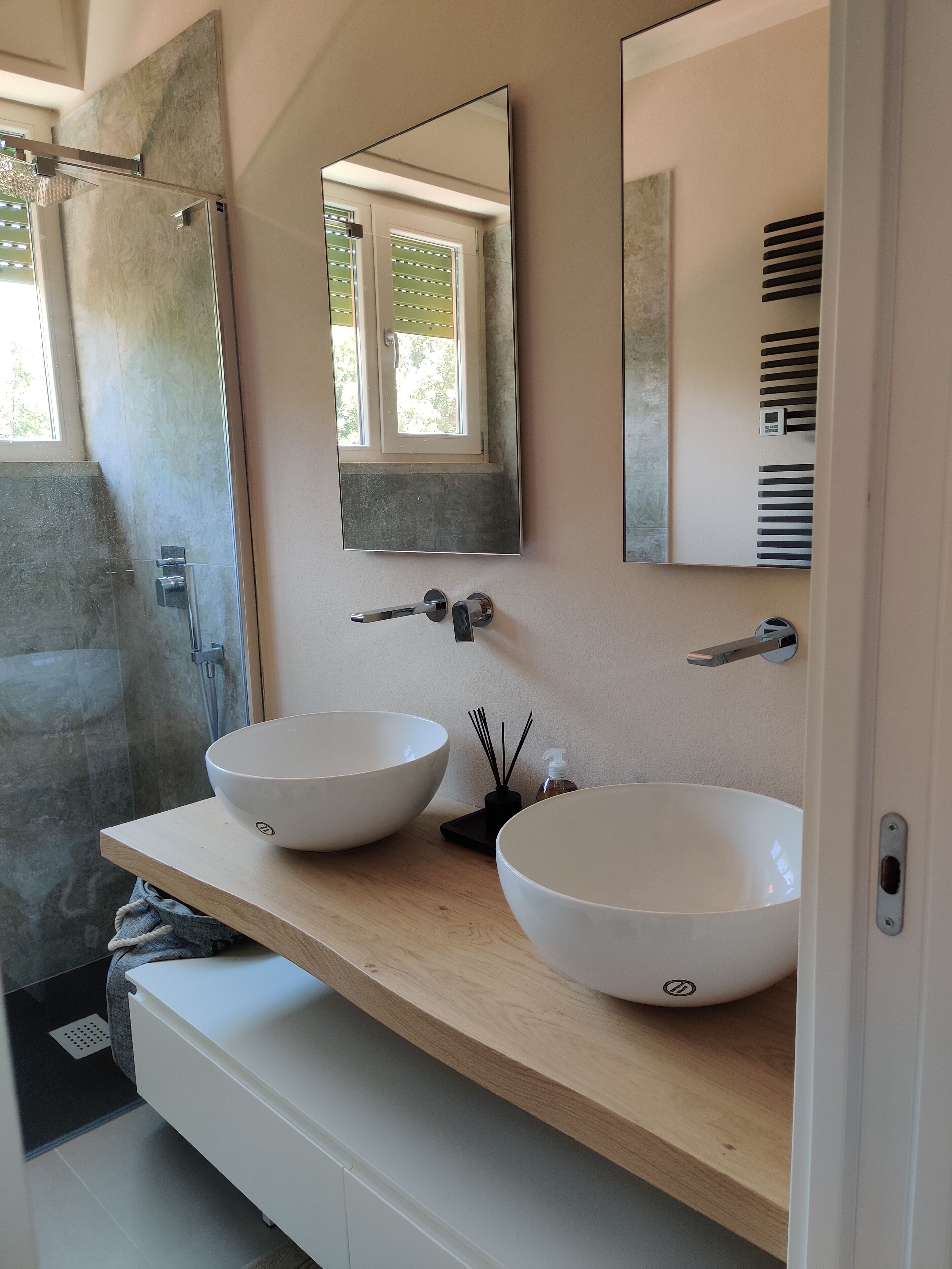 A bathroom with two white vessel sinks, a large mirror, and a shower area.