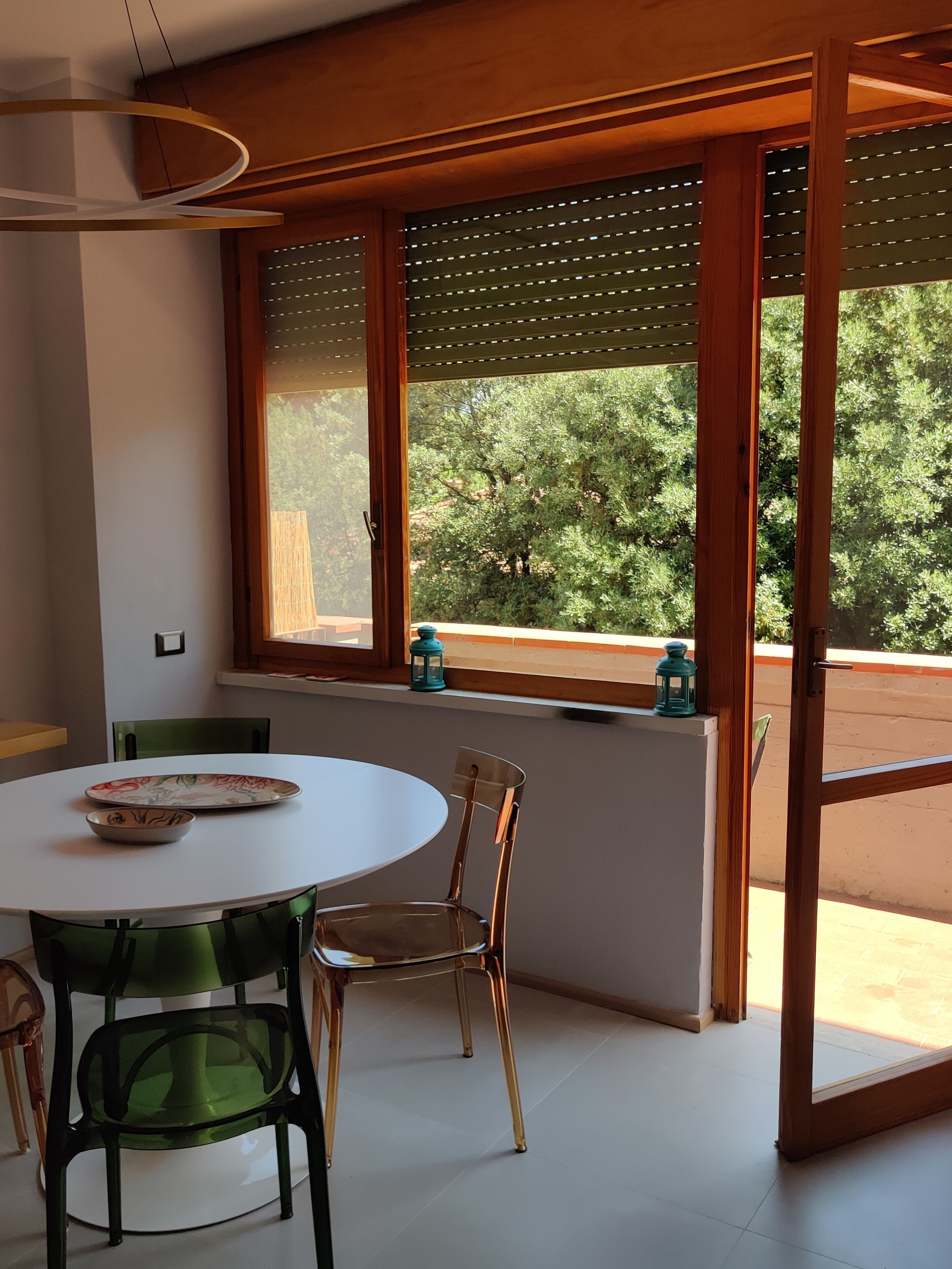 Un comedor con una mesa redonda, dos sillas y un ventanal con vistas a árboles.