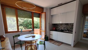Eine moderne Küche mit weißen Schränken, einer schwarzen Arbeitsplatte und einem Fenster mit Jalousien.