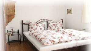 Un lit avec une couvre-lit à motifs floraux, une tête de lit en bois et une table de chevet avec une lampe.