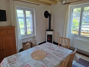 A room with a table covered by a patterned tablecloth, a woven basket, a wooden cabinet, and a black stove.