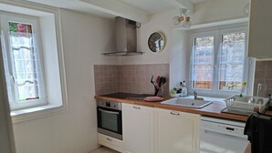 Una cocina con armarios blancos, estufa, lavaplatos y ventana con vistas.