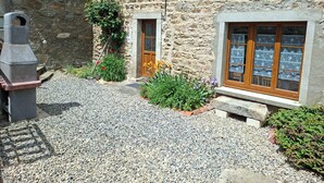 Un edificio de piedra con un patio de grava, una puerta de madera y una ventana con vidrio emplomado.