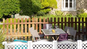 A patio with a table and chairs, a wooden fence, and a stone building in the background. - L'Emeraude by Interhome (Cancale)