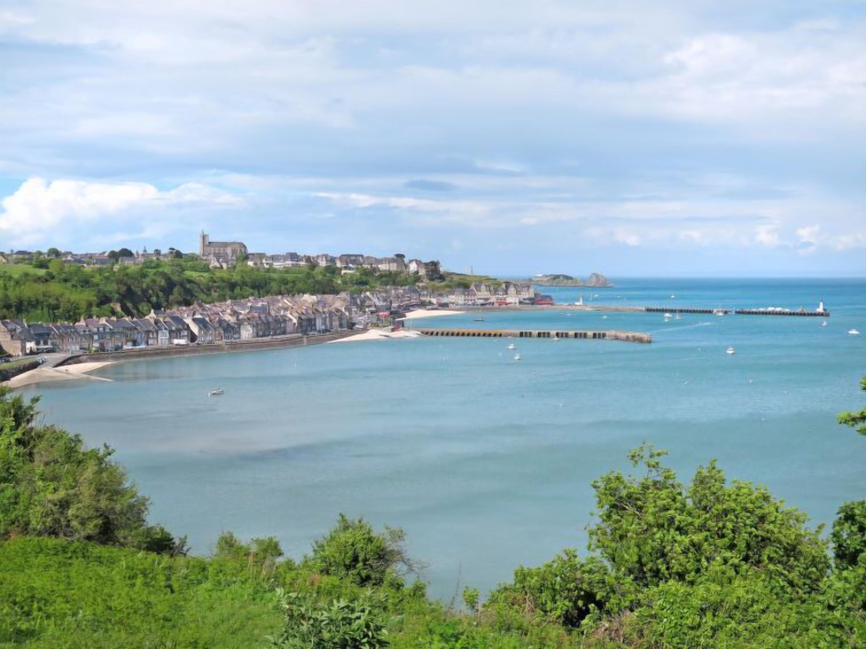 Un pueblo costero con playa, muelle e iglesia en una colina.