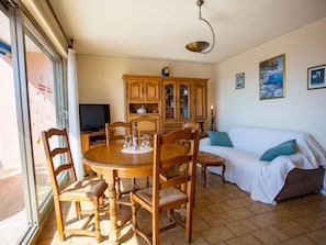 Ein gemütliches Wohnzimmer mit einem Holzespeisetisch, Stühlen, einem Fernseher und einem Schrank.