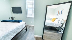 A bedroom with a bed, a TV mounted on the wall, and a window with blinds. - Fascinating 1BR/1 BA Near Festive DT and Riverwalk (San Antonio)