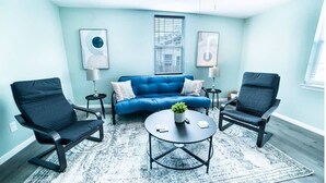 A living room with a blue sofa, two black chairs, a round coffee table, and a ceiling fan. - Fascinating 1BR/1 BA Near Festive DT and Riverwalk (San Antonio)