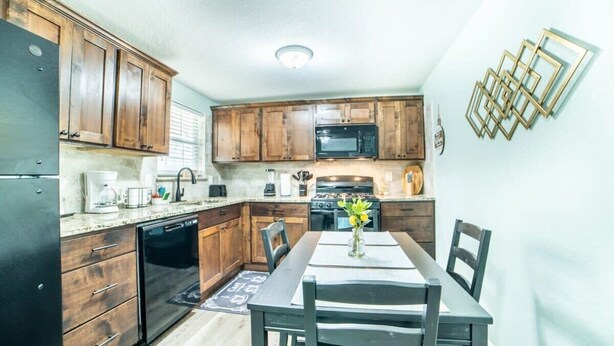 A kitchen with wooden cabinets, a microwave, a stove, and a dining table with chairs. - Fascinating 1BR/1 BA Near Festive DT and Riverwalk (San Antonio)