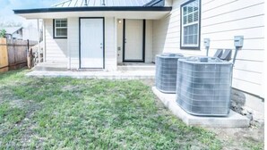 A residential house with a front porch, a garage door, and two air conditioning units in the yard. - Fascinating 1BR/1 BA Near Festive DT and Riverwalk (San Antonio)