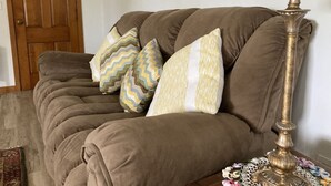 Un canapé marron agrémenté de plusieurs coussins, une lampe décorative et, au fond, une porte en bois.