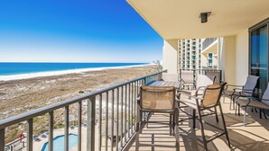 A balcony with a view of the beach and ocean, equipped with lounge chairs and a pool. - Phoenix 8 Beachfront Condo! (Orange Beach)