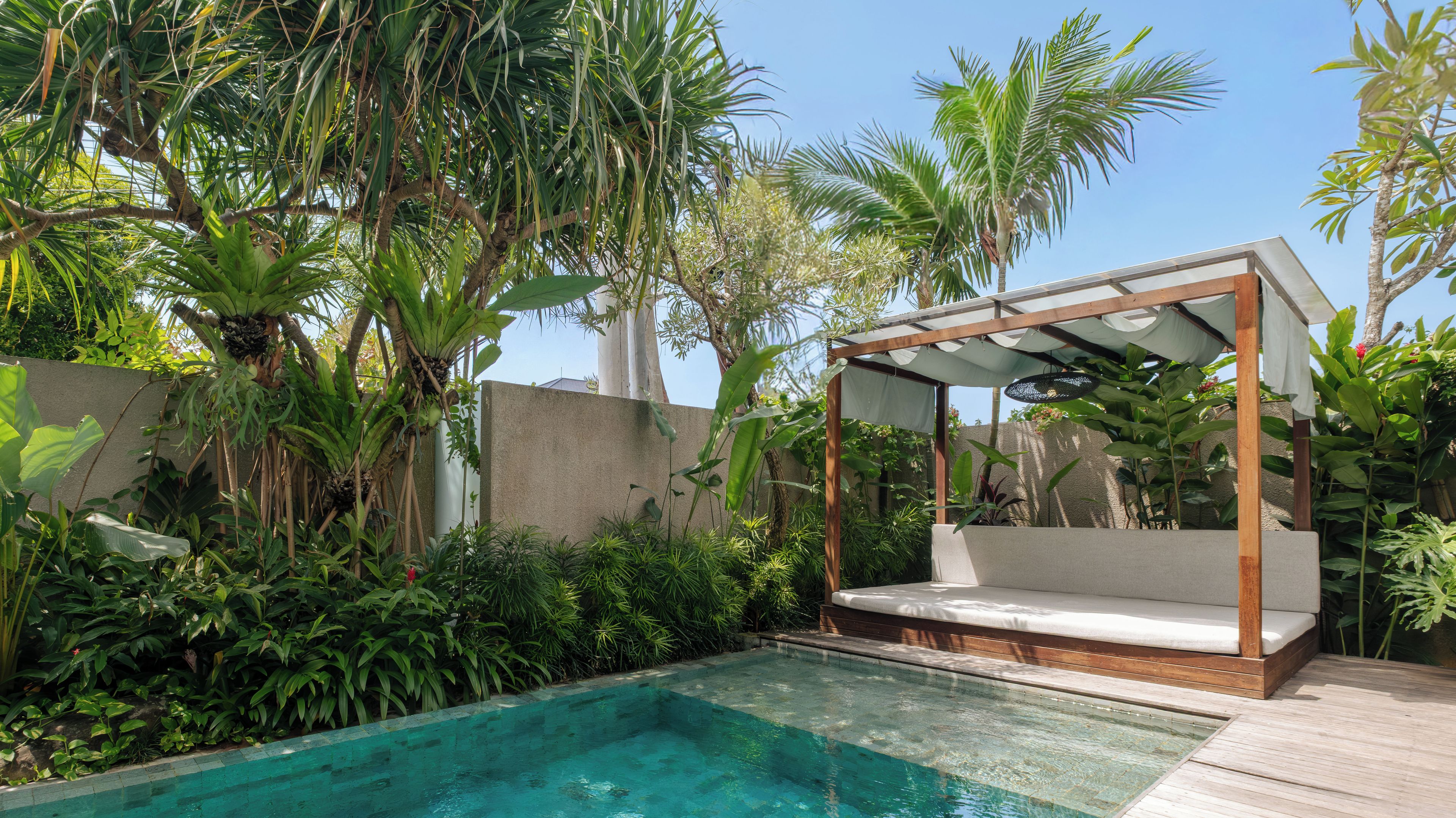 A pool with a wooden deck and a canopy seating area.