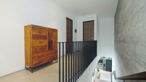 Ein modernes Interieur mit einem Holzschrank, einer Treppe mit schwarzer Geländer und einer Küchenzeile inklusive Kühlschrank und Spüle.