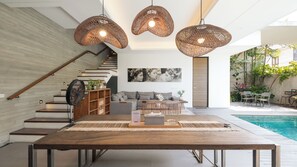 Un espacio de sala moderno con una mesa de madera, un sofá y una escalera.