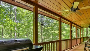 Una terraza techada al aire libre con una parrilla, barandillas de madera y ventiladores de techo.