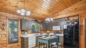 Cocina de cabaña de madera con una isla central, un refrigerador, un microondas y un lavamanos.