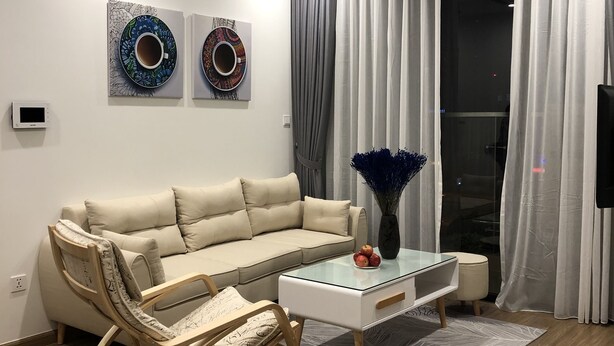 Un salon moderne avec un canapé beige, une table basse en verre et un fauteuil à bascule en bois.