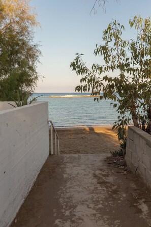 A concrete pathway leading to a beach with a view of the sea.