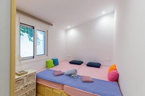 A room with two beds, a window, and a wooden cabinet.
