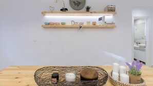 Une pièce avec une table en bois, une étagère murale ornée d’objets décoratifs, une horloge et un miroir.