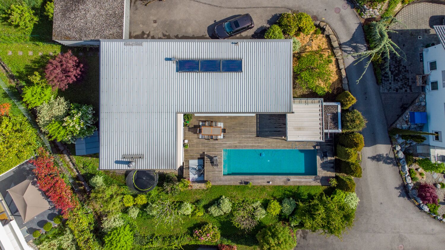 Ein modernes Haus mit Swimmingpool, einer Terrasse und einem Garten.