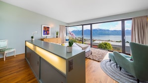 A modern room with a large window, a wooden floor, a sofa, a chair, and a small table with a plant. - Best Villa with Pool & Panoramic views (Lutry)