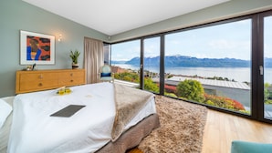 A bedroom with a large bed, a bedside table, a nightstand, a window with a view of mountains and a body of water. - Best Villa with Pool & Panoramic views (Lutry)