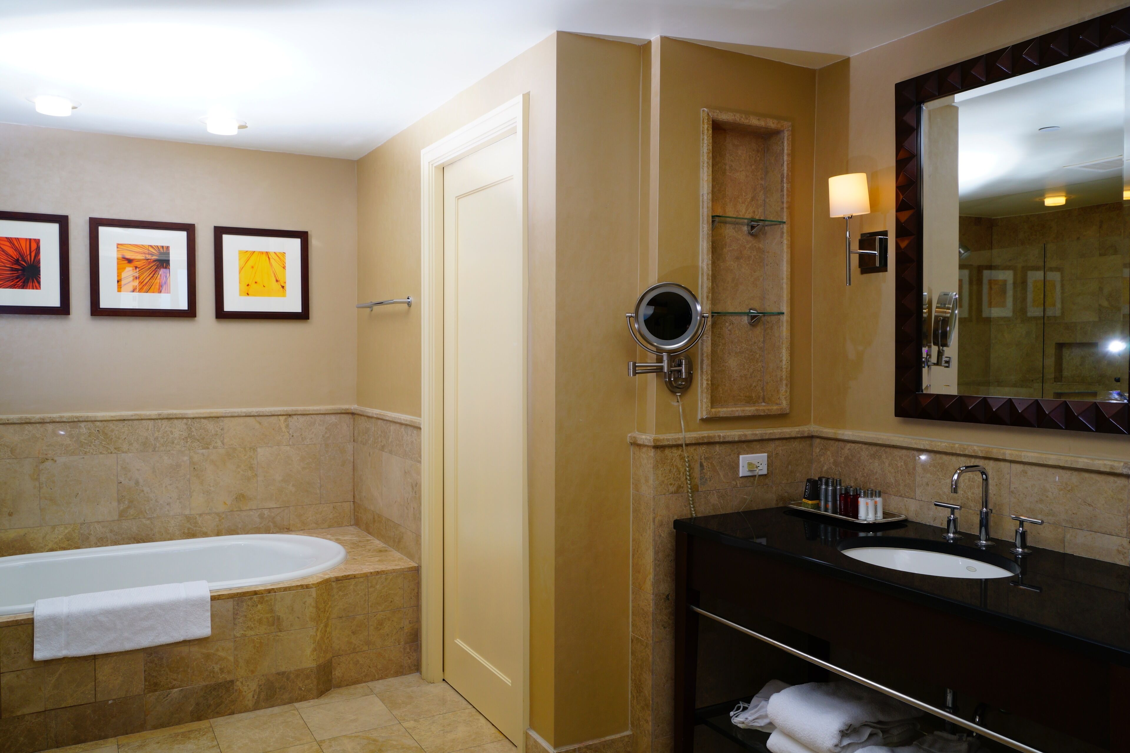 A bathroom with a bathtub, a sink, a mirror, and three framed pictures on the wall.
