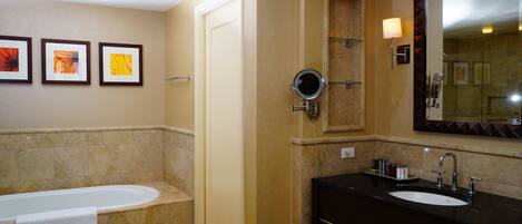 A bathroom with a bathtub, a sink, a mirror, and three framed pictures on the wall.
