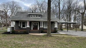 A two-story house with a front porch, a covered patio, and a flag. - The Gray House (Paducah)