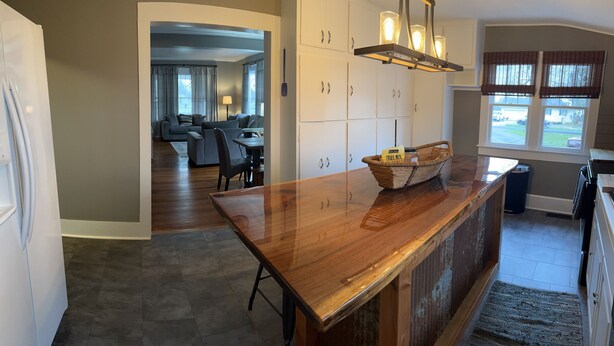 A kitchen with a wooden countertop, cabinets, and a dining area with a table and chairs. - The Gray House (Paducah)