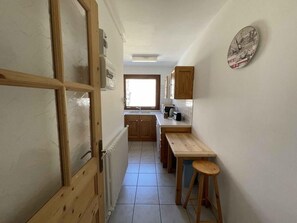 Compact kitchen with a toaster, sink, and stool, offering a convenient space for meal preparation.