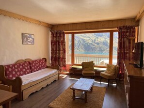 Relax in this inviting living room with a sofa, coffee table, and TV, offering a stunning view of the surrounding mountains.