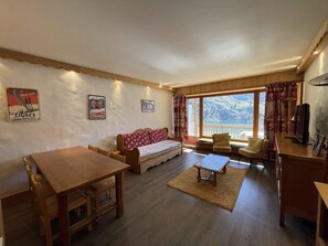 Relax in this inviting living room with a sofa, dining table, and TV, offering a view of the outdoors.