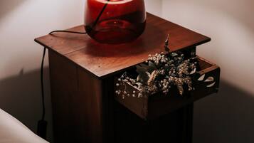 Uma mesa de cabeceira com abajur vermelho e uma caixa decorativa com flores.