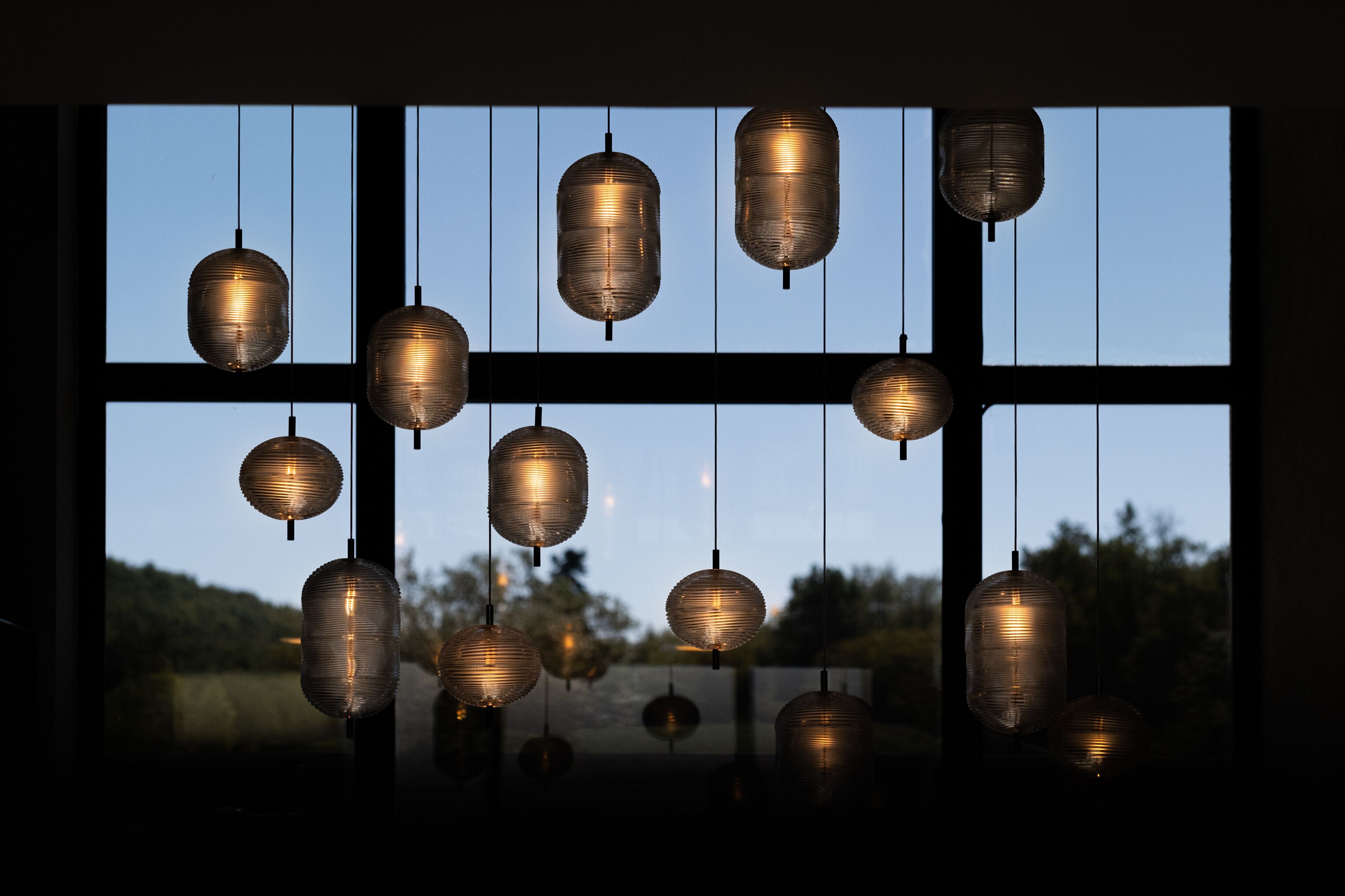 A series of hanging lanterns in a room with large windows.