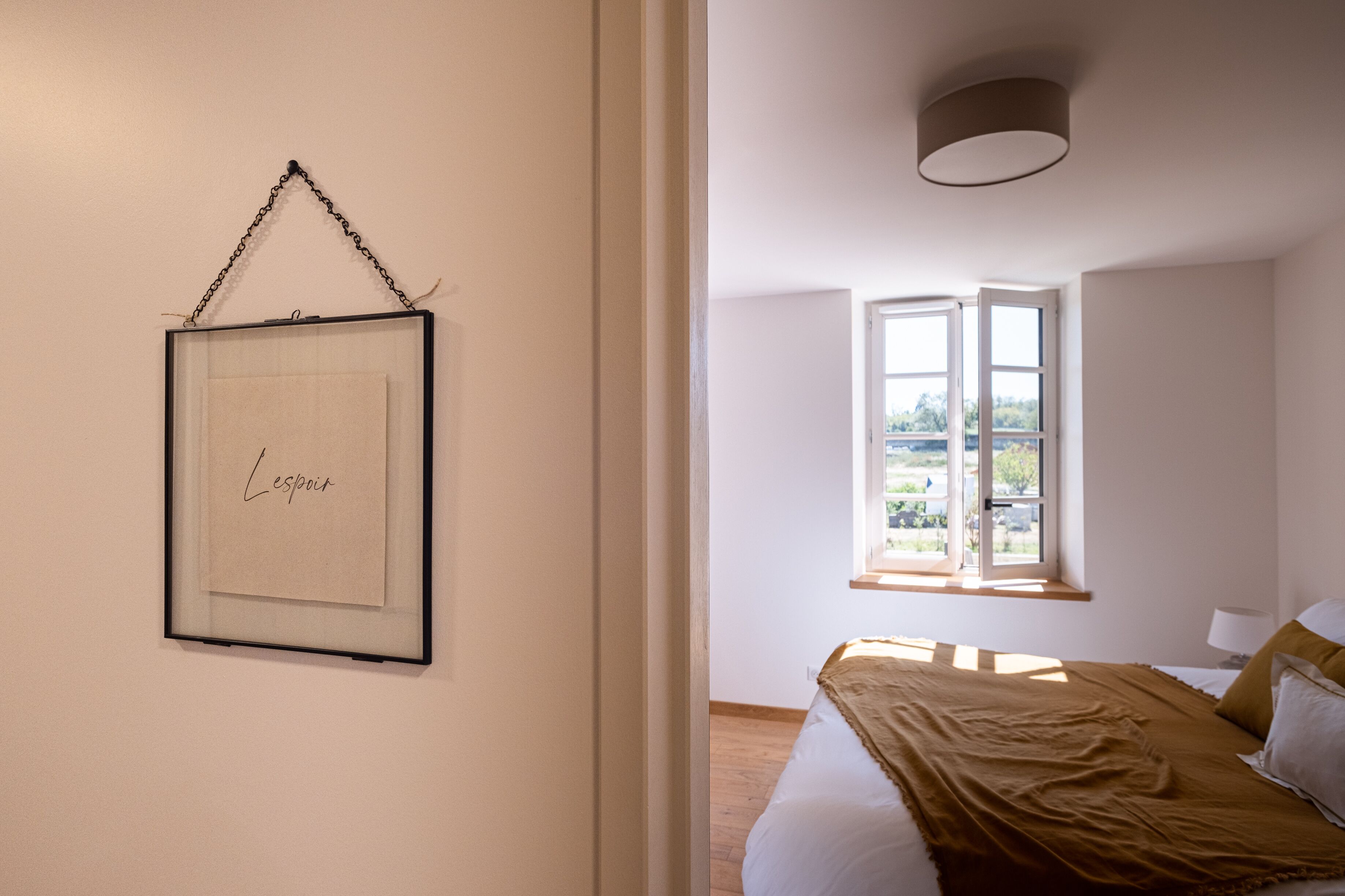 Un dormitorio con cama, ventana con vistas y un cuadro en la pared.