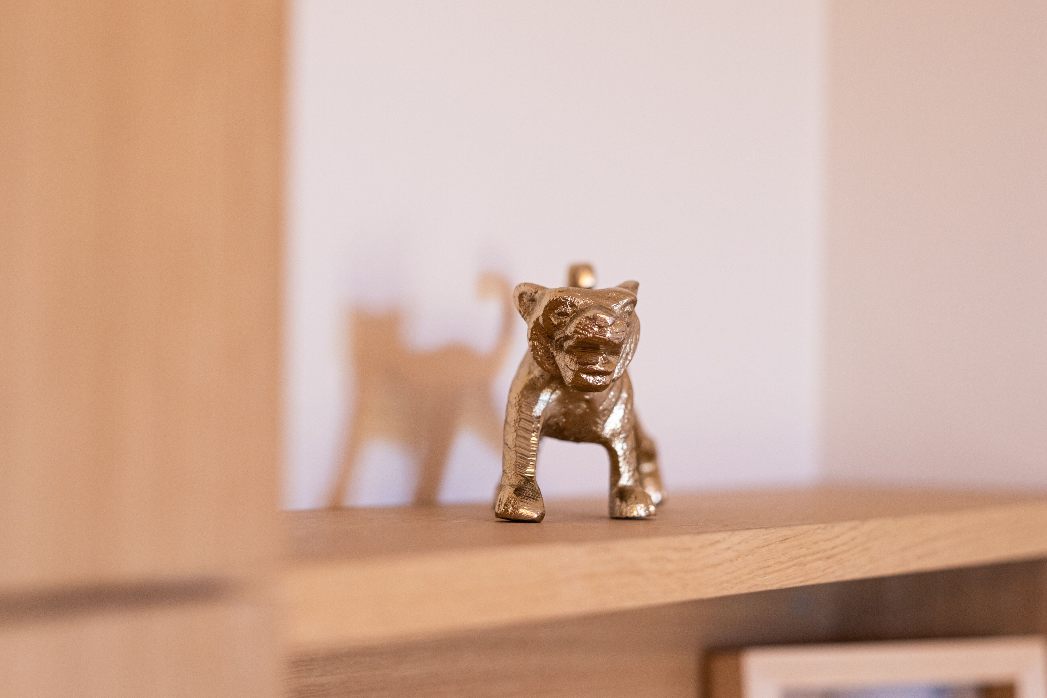 Uma pequena figura dourada de um urso em uma prateleira de madeira.