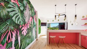 Cozinha moderna com uma ilha grande, piso de madeira e um mural tropical vibrante na parede.