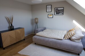 Un dormitorio con una cama, una mesita de noche, una lámpara y una pared decorada con cuadros.