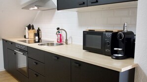 Una cocina moderna con gabinetes negros, microondas, cafetera y un lavamanos.