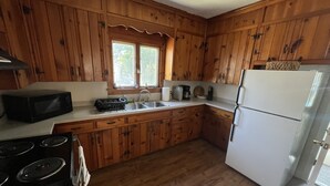 A kitchen with wooden cabinets, a white refrigerator, a stove, and a sink. - Charming 4 BD near DT Geneva (Geneva)