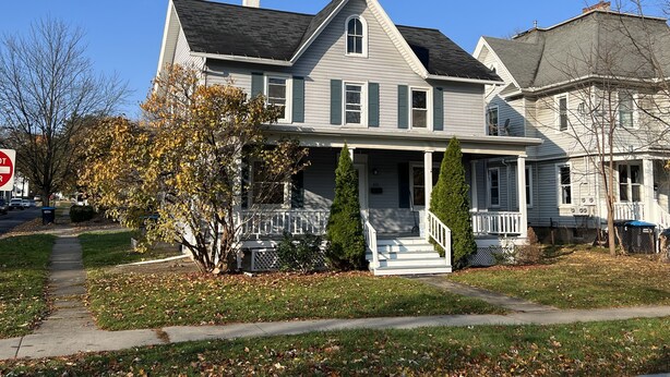 A two-story house with a front porch, a chimney, and a garage. - Charming 4 BD near DT Geneva (Geneva)
